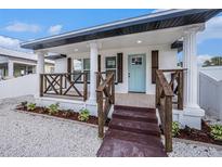 Charming front porch with decorative columns, wood railings, and a bright blue front door at 3010 Thelma St, Tampa, FL 33605