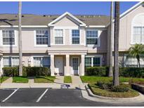 Inviting townhome featuring a well-manicured lawn, mature palms, and dedicated visitor parking at 415 Kensington Lake Cir, Brandon, FL 33511