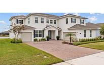 Stunning two-story home with a brick driveway, lush lawn and manicured landscaping at 7721 Roma Dune Dr, Wesley Chapel, FL 33545