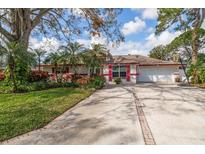 Charming single-story home with a well-manicured lawn, mature trees, and a spacious driveway with brick trim at 8636 15Th N Way, St Petersburg, FL 33702