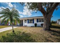 Charming single-story home with a well-maintained lawn, palm tree, and white exterior with blue shutters at 10022 Lily N St # N, Pinellas Park, FL 33782