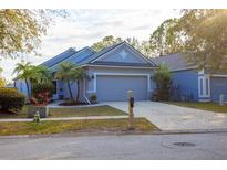 Charming single-story home with a well-manicured lawn, mature trees, and a two-car garage on a sunny day at 7603 Devonbridge Garden Way, Apollo Beach, FL 33572