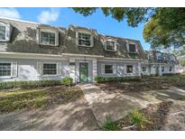 Charming two-story building featuring lush landscaping and a welcoming green door at 1710 Belleair Forest Dr # A, Belleair, FL 33756