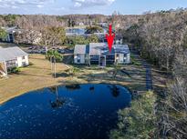 Scenic aerial view of condo complex with lush landscaping, lake and community parking at 1424 Pine Glen Ln # B2, Tarpon Springs, FL 34688