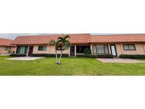 Charming, single-story condo with manicured lawn and tropical landscaping under a cloudy sky at 19029 Us Highway 19 N # 35E, Clearwater, FL 33764