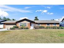 Charming brick home with a well-maintained lawn, colorful flowering bushes, and inviting front entrance at 2012 Cricket Ln, Valrico, FL 33594