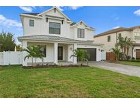 Elegant two-story white home with manicured lawn, dark-framed windows and a two car garage on a sunny day at 4114 W Inman Ave, Tampa, FL 33609