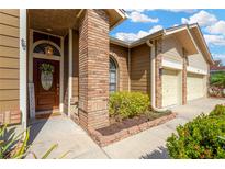 Charming home exterior showcasing brick accents, a two-car garage, and landscaped flowerbeds at 11209 Bloomington Dr, Tampa, FL 33635