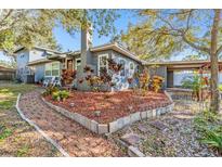 Charming home featuring a landscaped front yard with a brick pathway, stone accents, and mature trees at 1157 Brook Rd, Clearwater, FL 33755