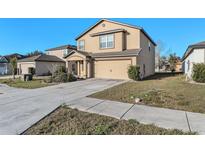 Two story house with a two car garage, well-maintained landscaping, and a concrete driveway on a sunny day at 14269 Lemon Yellow Tree Ln, Brooksville, FL 34613