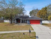 Charming single-story home boasts a red garage door and inviting entrance, complemented by a well-maintained front yard and lush trees at 16508 Round Oak Dr, Tampa, FL 33618
