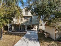 Inviting stilt home featuring a large driveway, shed, and a covered area for parking and outdoor seating at 6291 Sebring St, Weeki Wachee, FL 34607