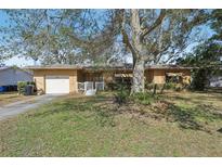 Charming single-story home with a well-maintained front yard and mature shade tree in sunny Florida at 1910 Rainbow Dr, Clearwater, FL 33765