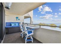 Cozy condo balcony with comfortable blue seating and a stunning view of the bay at 5915 Sea Ranch Dr # 703, Hudson, FL 34667