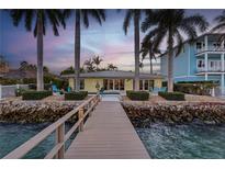 Charming waterfront home boasts a private dock and lush landscaping, perfect for enjoying serene sunsets at 11385 9Th E St, Treasure Island, FL 33706