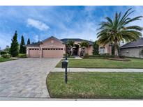 Charming home with a three-car garage, lush landscaping, and a brick-paved driveway at 2903 Marble Crest Dr, Land O Lakes, FL 34638