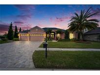 Charming home with a three-car garage, lush landscaping, and a brick-paved driveway at 2903 Marble Crest Dr, Land O Lakes, FL 34638