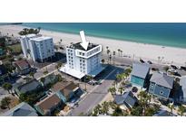 A stunning, sun-drenched aerial view of a multi-story condo building near a beautiful beach at 555 Gulf Way # 7N, St Pete Beach, FL 33706