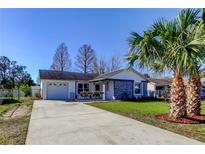 Charming single-story home boasts a well-maintained front yard with a vibrant palm tree and cozy front porch at 7148 Jenner Ave, New Port Richey, FL 34655