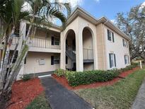 Beige two-story condo with archways, palm tree, manicured bushes, and mulch landscaping at 10346 Carrollwood Ln # 171, Tampa, FL 33618