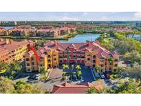 Beautiful aerial view of a waterfront condo building with red tile roof, lush landscaping, and surface parking at 2717 Via Cipriani # 620A, Clearwater, FL 33764