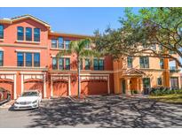 View of an orange, three-story townhouse with garage and a white car parked out front at 2717 Via Cipriani # 623B, Clearwater, FL 33764