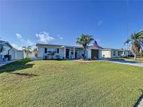 Charming single Gathering home with a well-maintained lawn, palm tree and an American flag at 3142 Domino Dr, Holiday, FL 34691