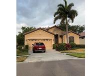 Charming single Gathering home with a two car garage, red car parked in driveway and lush landscaping at 116 Silver Falls Dr, Apollo Beach, FL 33572