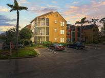 View of the condo building with palm trees, parking, and balconies under a vibrant, colorful sunset sky at 11901 4Th N St # 7307, St Petersburg, FL 33716