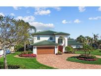 Stunning two-story home with green roof, brick driveway, lush landscaping, and a two-car garage at 1930 Kansas Ne Ave, St Petersburg, FL 33703