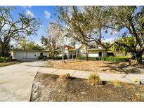 Charming single-story home with a red tile roof, lush greenery, and a spacious driveway at 4811 Paradise S Way, St Petersburg, FL 33705