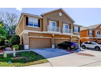 Inviting townhome featuring a two-car garage and a charming front facade with small balconies above the garages at 7510 Red Mill Cir, New Port Richey, FL 34653