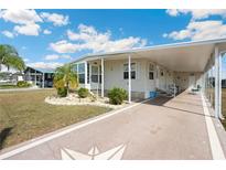 Charming manufactured home features a covered parking area, landscaped yard and inviting entrance at 5238 Mary St, Zephyrhills, FL 33542