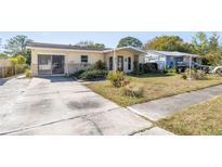 Charming single-story home with a yellow exterior, stone accents, and a spacious driveway at 4408 W Lackland Pl, Tampa, FL 33616