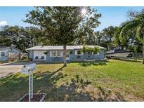 A cozy single-Gathering home with a metal roof, green lawn, mailbox, and a boat parked in the yard at 5410 Tangerine Dr, Zephyrhills, FL 33542