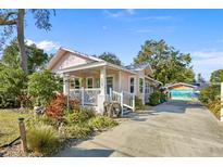 Charming pink bungalow featuring a cozy front porch and lush, colorful landscaping at 1166 Granada St, Clearwater, FL 33755