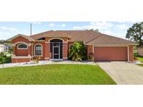 Charming single-story home featuring a well-manicured lawn, two car garage, and a screened in front entryway at 13481 Pullman Dr, Spring Hill, FL 34609