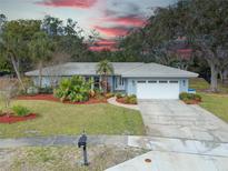 Charming one story home with a two car garage, lush landscaping, and inviting curb appeal at 1854 Wateroak W Dr, Clearwater, FL 33764