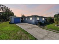 Charming single-story home featuring a blue garage door, well-maintained lawn, and a spacious driveway at 214 Driftwood N Dr, Palm Harbor, FL 34683