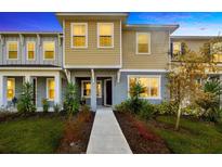 Inviting two-story townhome with a well-maintained lawn, landscaping, and a sidewalk leading to the front door at 5080 Avalon Park Blvd, Wesley Chapel, FL 33545