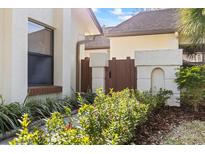 Inviting home side view with charming brown fence, lush landscaping, and a serene walkway at 14766 Feather Cove Ln, Clearwater, FL 33762