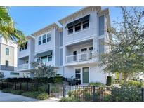 Charming three-story townhome featuring a balcony, awning, and green door, complemented by lush landscaping and a black metal fence at 2510 W Cleveland St # 3, Tampa, FL 33609