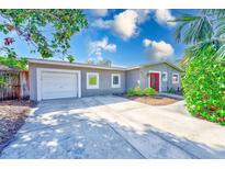 Charming single-story home featuring a bright red front door, a garage, and a well-maintained lawn at 4606 W Oakellar Ave, Tampa, FL 33611