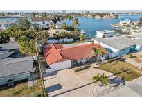 Beautiful waterfront home featuring a red tile roof, brick driveway, and lush tropical landscaping at 619 59Th Ave, St Pete Beach, FL 33706