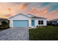 Charming one-story home featuring a blue garage door and matching front door with fresh green grass and a brick paved driveway at 1018 Blakley St, Punta Gorda, FL 33980