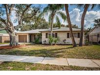 Charming single-story home featuring a well-maintained lawn and beautiful, mature landscaping with trees and mulch at 4807 Wynwood Dr, Tampa, FL 33615