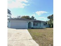 Charming single-story home with light blue paint, arched entryway, and a wide driveway leading to an attached garage at 7044 Everest St, Spring Hill, FL 34606