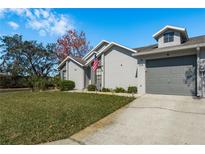 Beautiful home with a well-maintained lawn, neutral paint, an American flag, and an attached one-car garage at 7536 Roland Ct, New Port Richey, FL 34654