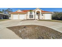 Charming single Gathering home featuring an attached two-car garage, desert landscaping, and a circular driveway at 9234 Duffer Ct, Hudson, FL 34667