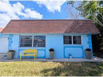 Charming home with a blue exterior, brown roof, a cozy yellow bench, and potted plants at 8445 Jeffrey N # 8445, Pinellas Park, FL 33781